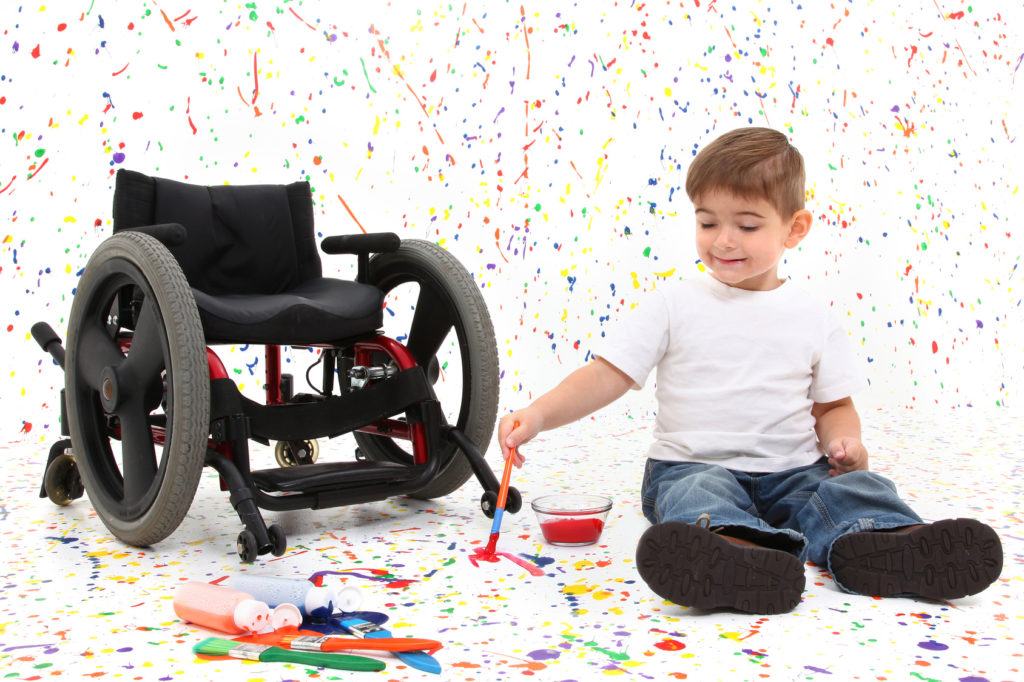 Child playing with wheelchair in background