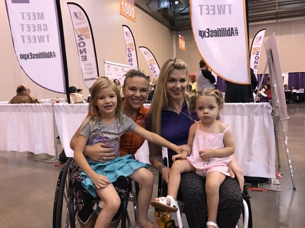 Two ladies in wheelchairs holding their daughters