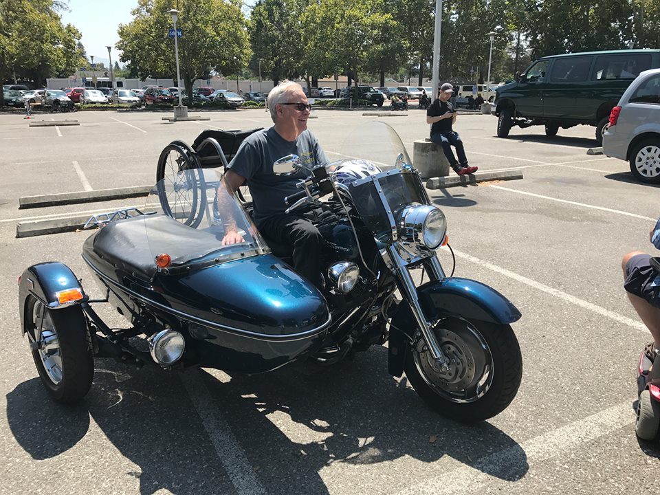 Man on motorcycle with sidecar and wheelchair 