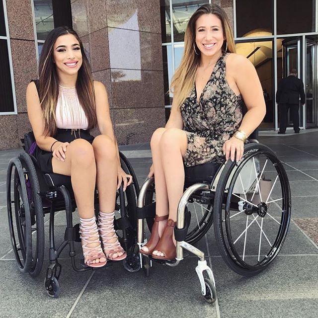 Two ladies in wheelchairs wearing fashionable clothes and shoes