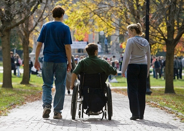 Young man in wheelchair on college campus with friends