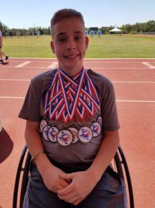 kid in wheelchair wearing many medals