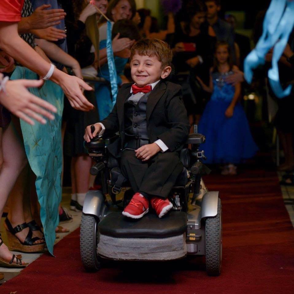 boy in powered wheelchair on red carpet