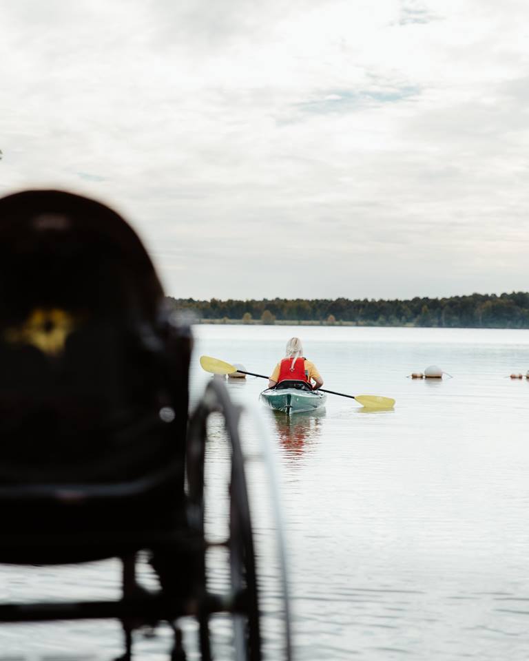 woman paddling kayak with wheelchair in the foreground