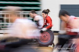 Kristen Cameron playing wheelchair rugby in a ponytail and red jersey