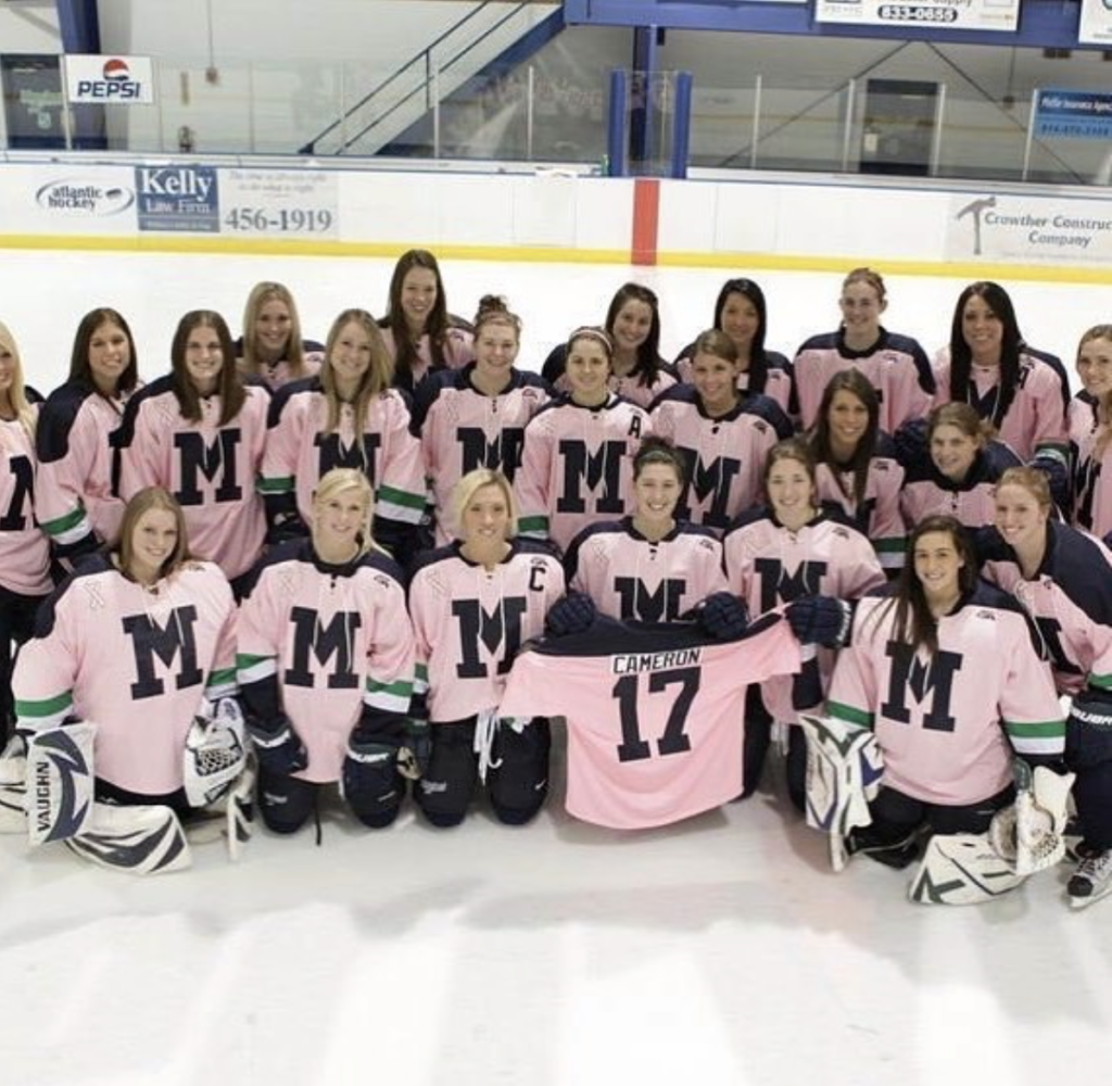 A women's hockey team. All wearing pink Mercyhurst jerseys and posing with a jersey number 17 with Cameron on the back.