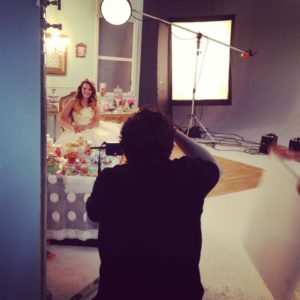 Jessica posing in a fluffy dress surrounded by large sweets in a photoshoot for Lise Watier