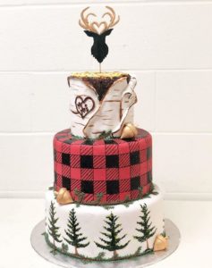 Three tiered wedding cake featuring trees, buffalo plaid and birch bark icing